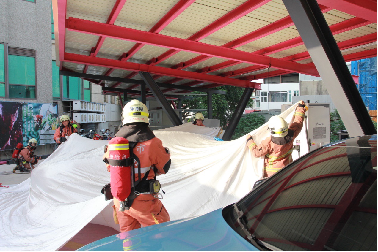 消防隊員專業迅速地以防火毯覆蓋電動車 消防隊員專業迅速地以防火毯覆蓋電動車